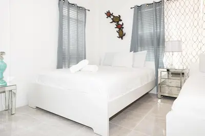 a white bedroom with a white bed and two tables at Apartments on Ocean Drive in Miami Beach