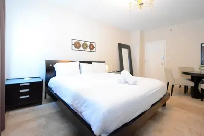 a bedroom with a large white bed with a table at Apartments on Ocean Drive in Miami Beach