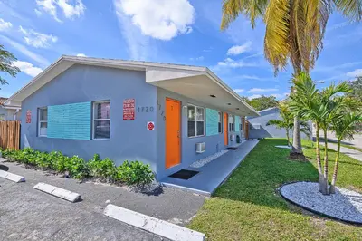 a blue house with an orange door and palm trees at Relax and enjoy Fort Lauderdale beach! in Fort Lauderdale