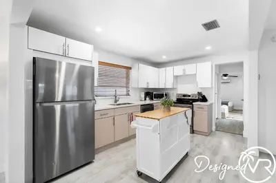 a kitchen with a stainless steel refrigerator and white cabinets at 4BR retreat w heated pool backyard BBQ grill in Dania Beach
