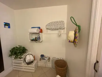 a bathroom with a white wall with shelves and a plant at Chic and Comfortable Studio Free Street Parking in Miami