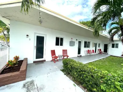 a white house with red chairs and a patio at Private Studio blocks from Coconut Grove in Miami