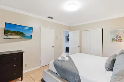 a white bedroom with a bed and a dresser at The Home in The Oaks - By Avi in Fort Lauderdale