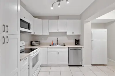a white kitchen with a sink and a refrigerator at The Home in The Oaks - By Avi in Fort Lauderdale