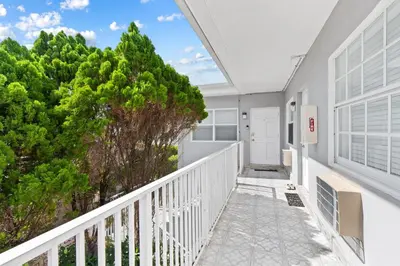 a white house with a balcony with trees at Cozy studio wbeach boardwalk steps kitchen in Hollywood