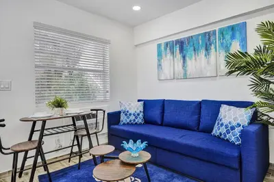 a living room with a blue couch and a table at Cozy studio wbeach boardwalk steps kitchen in Hollywood