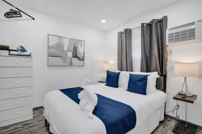 a bedroom with a large bed with blue pillows at Cozy studio wbeach boardwalk steps kitchen in Hollywood