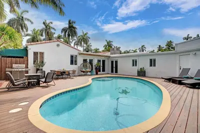 a swimming pool on a wooden deck next to a house at Family home wpool tiki hut grill in Hollywood