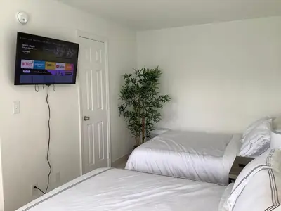 a bedroom with two beds and a flat screen tv at Hotel Motel Lauderdale Inn in Fort Lauderdale