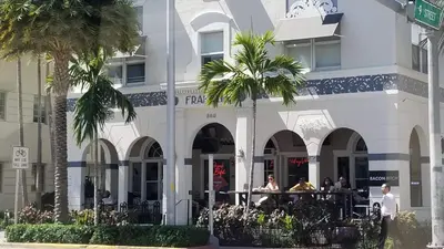 a white building with palm trees in front of it at VERSACE MANSION VIEW SUITE at THE STRAND in Miami Beach