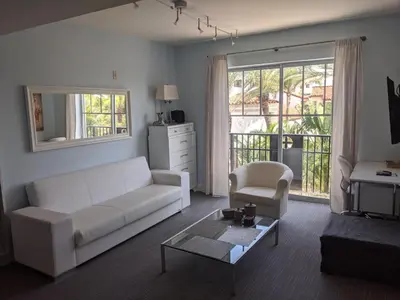 a living room with a white couch and a chair at VERSACE MANSION VIEW SUITE at THE STRAND in Miami Beach