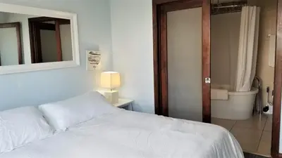 a bedroom with a white bed and a bathroom at VERSACE MANSION VIEW SUITE at THE STRAND in Miami Beach