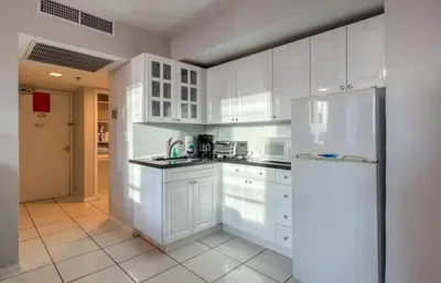 a kitchen with white cabinets and a refrigerator at Castle 705 in Miami Beach