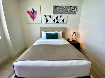 a bedroom with a large white bed with a blue pillow at Luxury Condo with Jacuzzi and Amenities in Hollywood