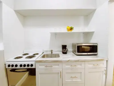 a white kitchen with a stove and a microwave at Miami International by Lowkl in Miami Beach