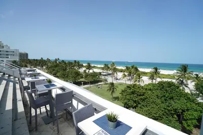 a balcony with tables and chairs and the beach at Deluxe apartments at the Congress in Miami Beach