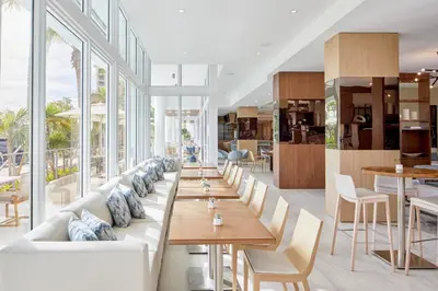 a restaurant with white couches and tables and windows at AC Hotel by Marriott Fort Lauderdale Beach in Fort Lauderdale