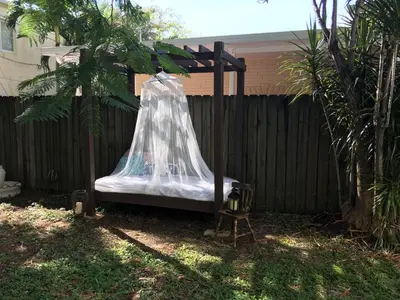 a canopy bed in a yard next to a fence at Heavenly Suite in Little Havana Free Parking in Miami