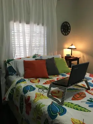 a bedroom with a bed with a laptop on it at The Jewel of Little Havana in Miami