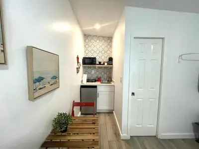 a hallway with a white door and a red chair at Studio close to Everything in Miami