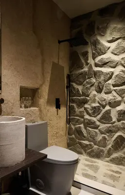 a stone bathroom with a toilet and a stone wall at Casa Kawa lumicollection in Miami