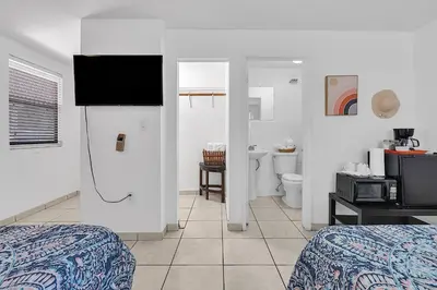 a room with two beds and a bathroom with a television at Boho Studio in Little Havana in Miami