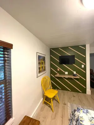 a room with a yellow chair and a tv on a wall at Cozy Room in the Heart of Little Havana in Miami