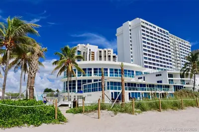 a large building on the beach with palm trees at Girasole Rentals in Miami Beach
