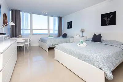 a white bedroom with two beds and a desk at Girasole Rentals in Miami Beach