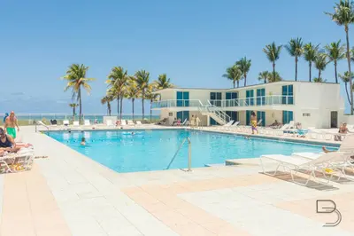a swimming pool with palm trees and a building at Girasole Rentals in Miami Beach