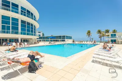 a group of people laying in lawn chairs by a pool at Girasole Rentals in Miami Beach