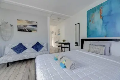 a white bedroom with a large bed and a table at Adorable private apartments in the Heart of Miami! in Miami