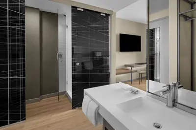 a bathroom with a sink and a shower with a mirror at AC Hotel by Marriott Miami Dadeland in Miami