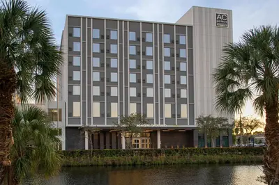 a building with palm trees in front of a river at AC Hotel by Marriott Miami Dadeland in Miami
