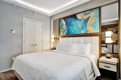 a bedroom with a white bed and a painting on the wall at Coastal studio w hot tub gym access in Fort Lauderdale