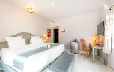a white bedroom with a large bed and a desk at Secret Garden Miami Beach in Miami Beach