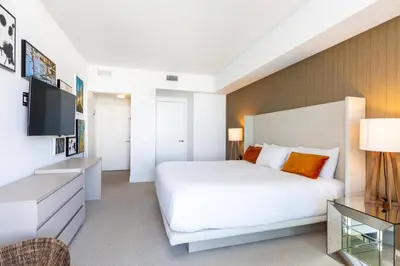 a bedroom with a large white bed and a television at Ocean view 1 bed- Steps from the beach! in Hallandale Beach