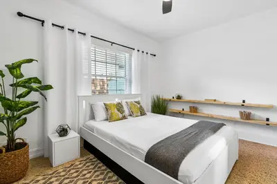 a white bedroom with a white bed and a plant at Alani Bay Villas in Fort Lauderdale