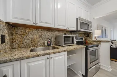 a kitchen with white cabinets and a sink and a microwave at Alani Bay Villas in Fort Lauderdale