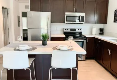 a kitchen with a island with two white bar stools at Spacious entire Apartment with Free Parking in Hollywood