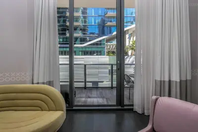 a living room with a yellow chair and a large window at Aluna Lux Suites at SLS Lux Brickell Building in Miami