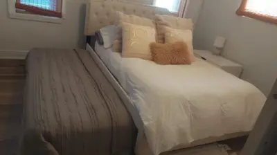a bed with white sheets and pillows in a bedroom at Little “house” right on the beach in Hollywood