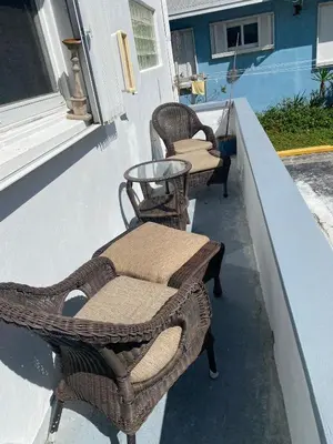 two wicker chairs and a table on a porch at Little “house” right on the beach in Hollywood