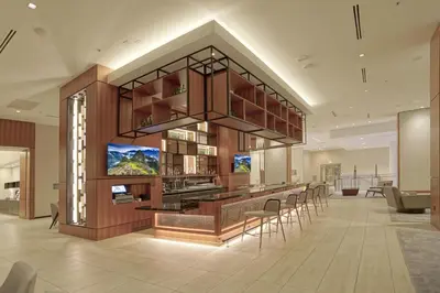 a lobby with a bar and chairs in a building at AC Hotel by Marriott Fort Lauderdale Airport in Dania Beach