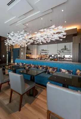 a restaurant with a blue couch and tables and chairs at Marriott Fort Lauderdale Airport in Dania Beach