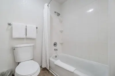 a white bathroom with a toilet and a bath tub at Doral Inn & Suites Miami Airport West in Miami
