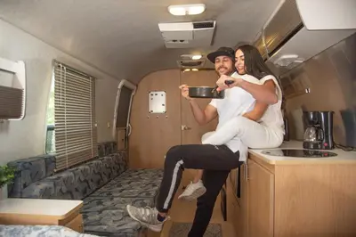 a man and a woman sitting on a kitchen in an rv at Airstream in the Center of it All in Miami