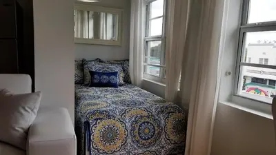 a bedroom with a bed in a room with two windows at SOBE SUNSHINE ONE BEDROOM APARTMENTs in Miami Beach