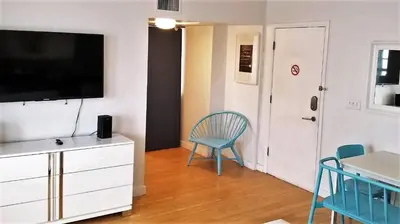 a living room with a tv and a blue chair at SOBE SUNSHINE ONE BEDROOM APARTMENTs in Miami Beach