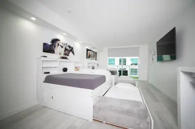 a white bedroom with a large bed and a tv at Modern and Luxurious Brickell Studio in Miami